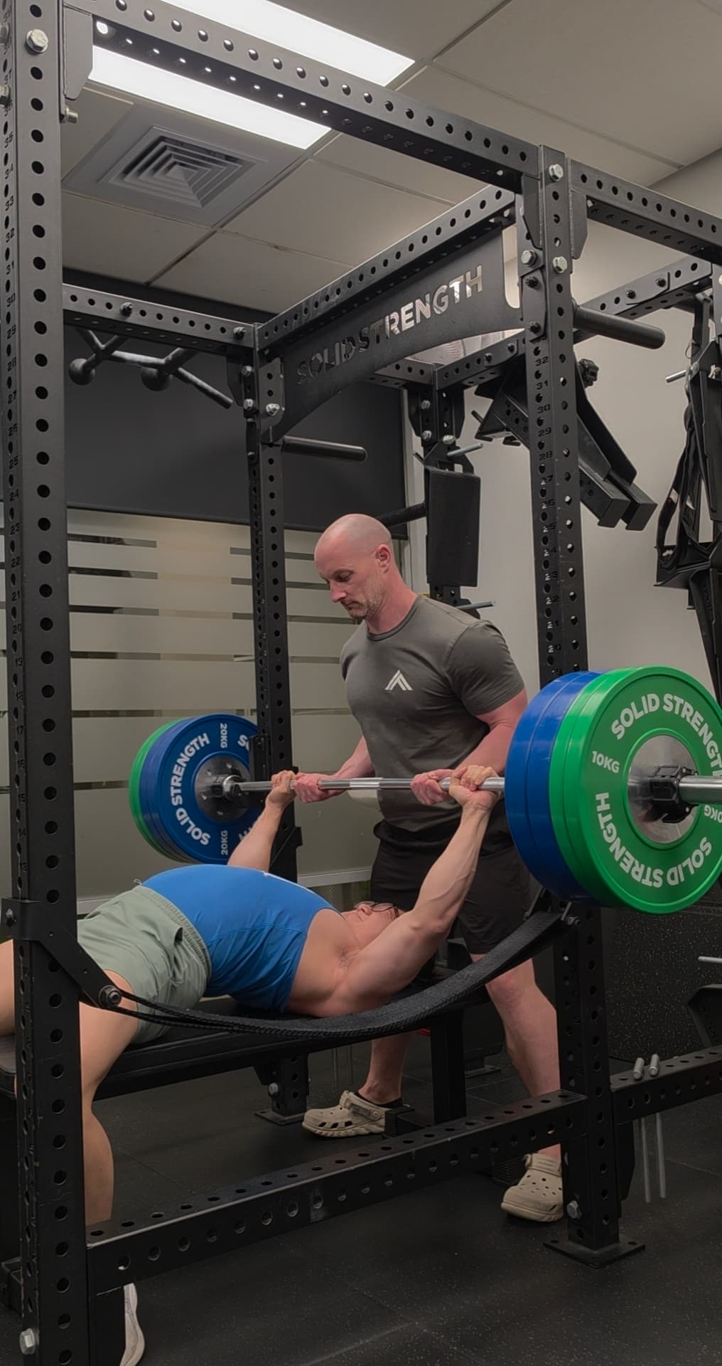 Coach spotting a client on the bench press at Iron Focus