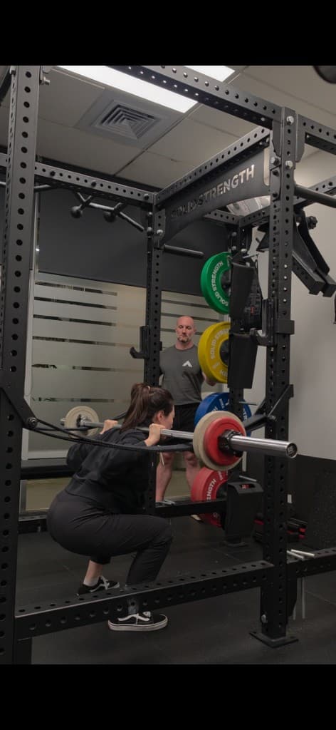Coach spotting a client on the barbell squat at Iron Focus