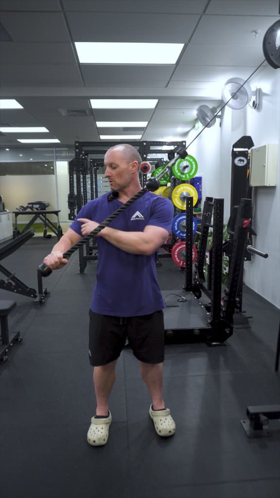 Coach demonstrating cable triceps work at Iron Focus Gym